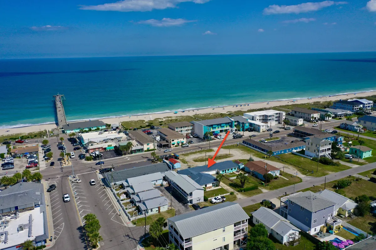 A scenic exterior shot showcasing an ocean view with the iconic pier in the background and nearby buildings, evoking the essence of beachside adventures and the inviting proximity of local attractions.