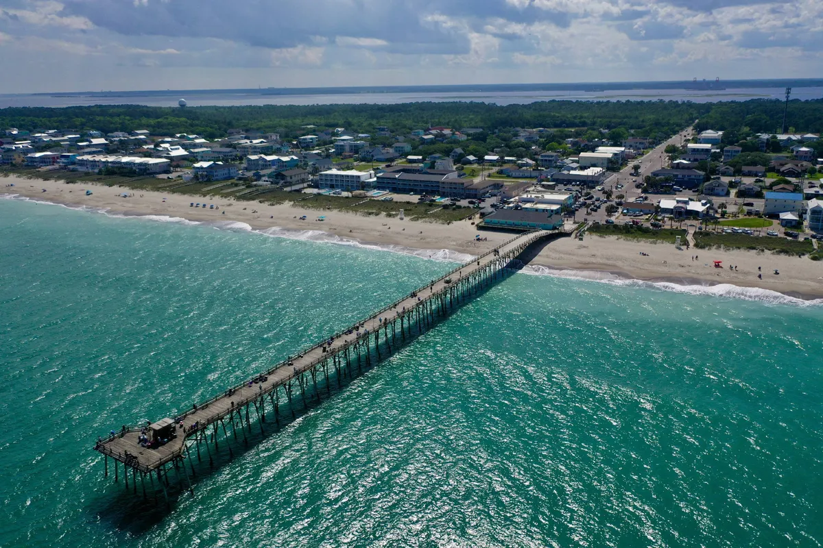 A relaxed exterior image featuring the pier, expansive beach, and the inviting town atmosphere, with plenty of space for sunbathing, beach games, or strolling together.